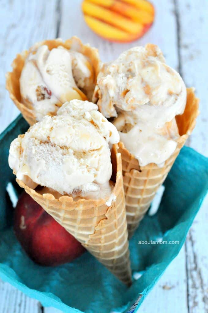 Three scoops of grilled peach ice cream in waffle cones, with fresh and grilled peaches.