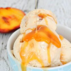 Scoops of grilled peach ice cream in a blue bowl, drizzled with caramel sauce.