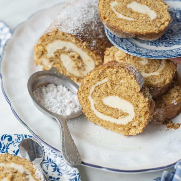 A gluten-free pumpkin roll with cream cheese filling, dusted with powdered sugar, and sliced.