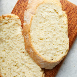 Two slices of golden-crusted Air-Fryer Bread on a wooden cutting board.