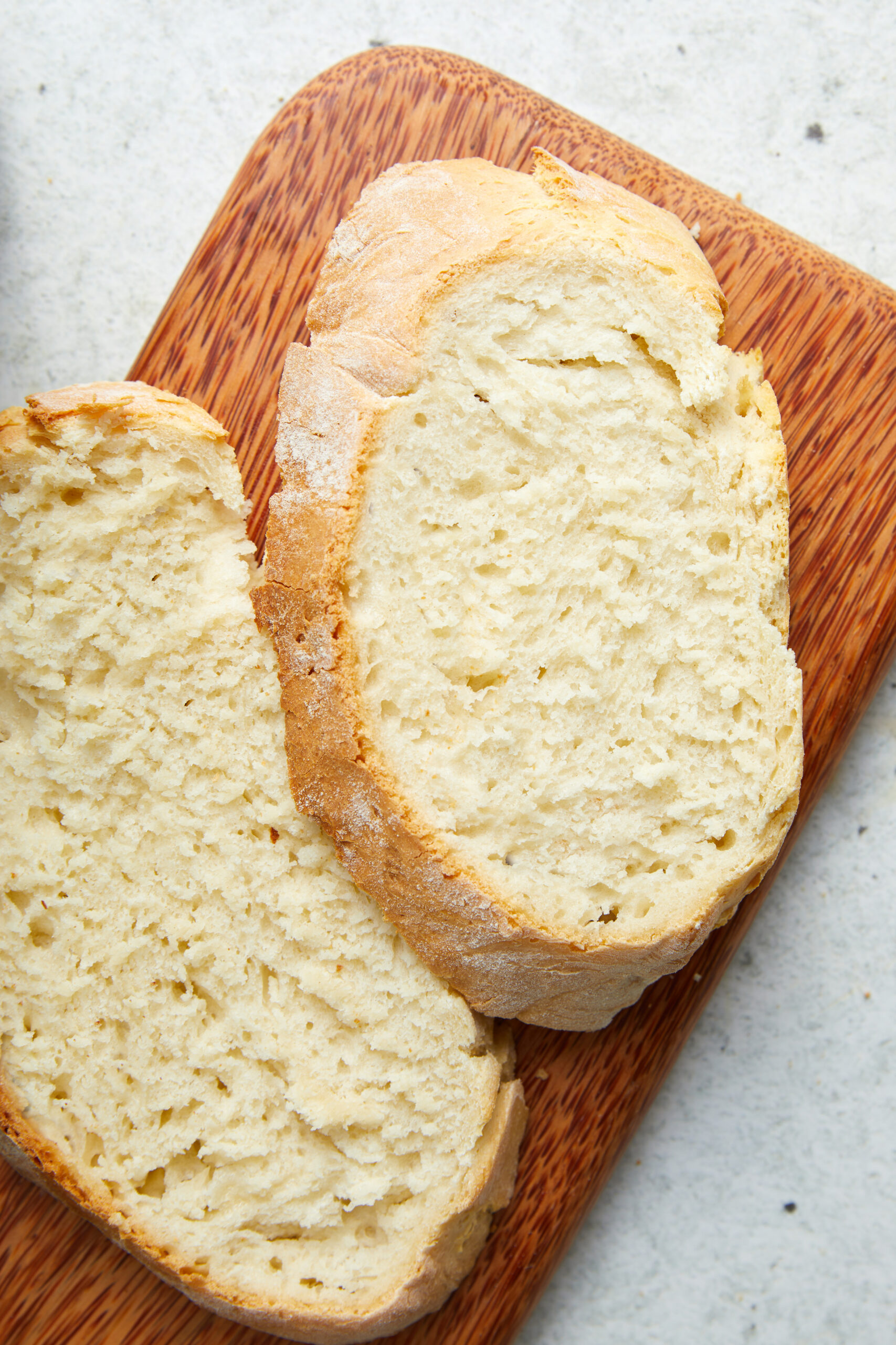 Two slices of golden-crusted Air-Fryer Bread on a wooden cutting board.