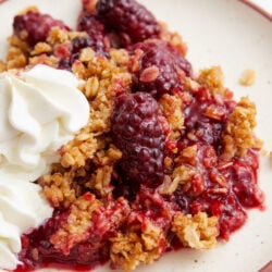Blackberry crisp served on a plate with a dollop of whipped cream.