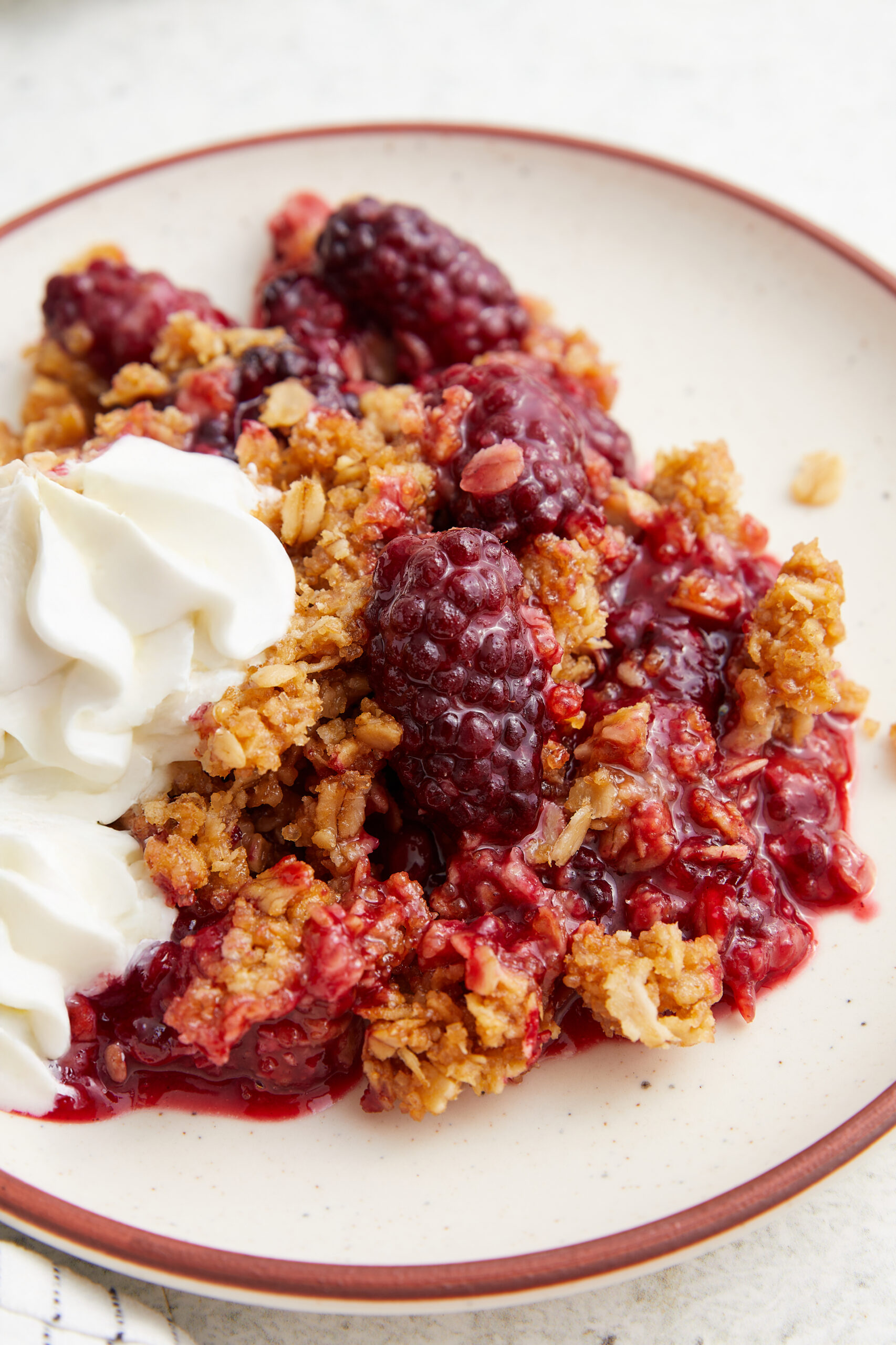 Blackberry crisp served on a plate with a dollop of whipped cream.