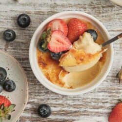 Cr&egrave;me br&ucirc;l&eacute;e with a caramelized sugar crust, garnished with fresh strawberries and blueberries.