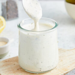 Homemade Ranch Dressing being scooped from a glass jar with a spoon, showing its creamy texture.