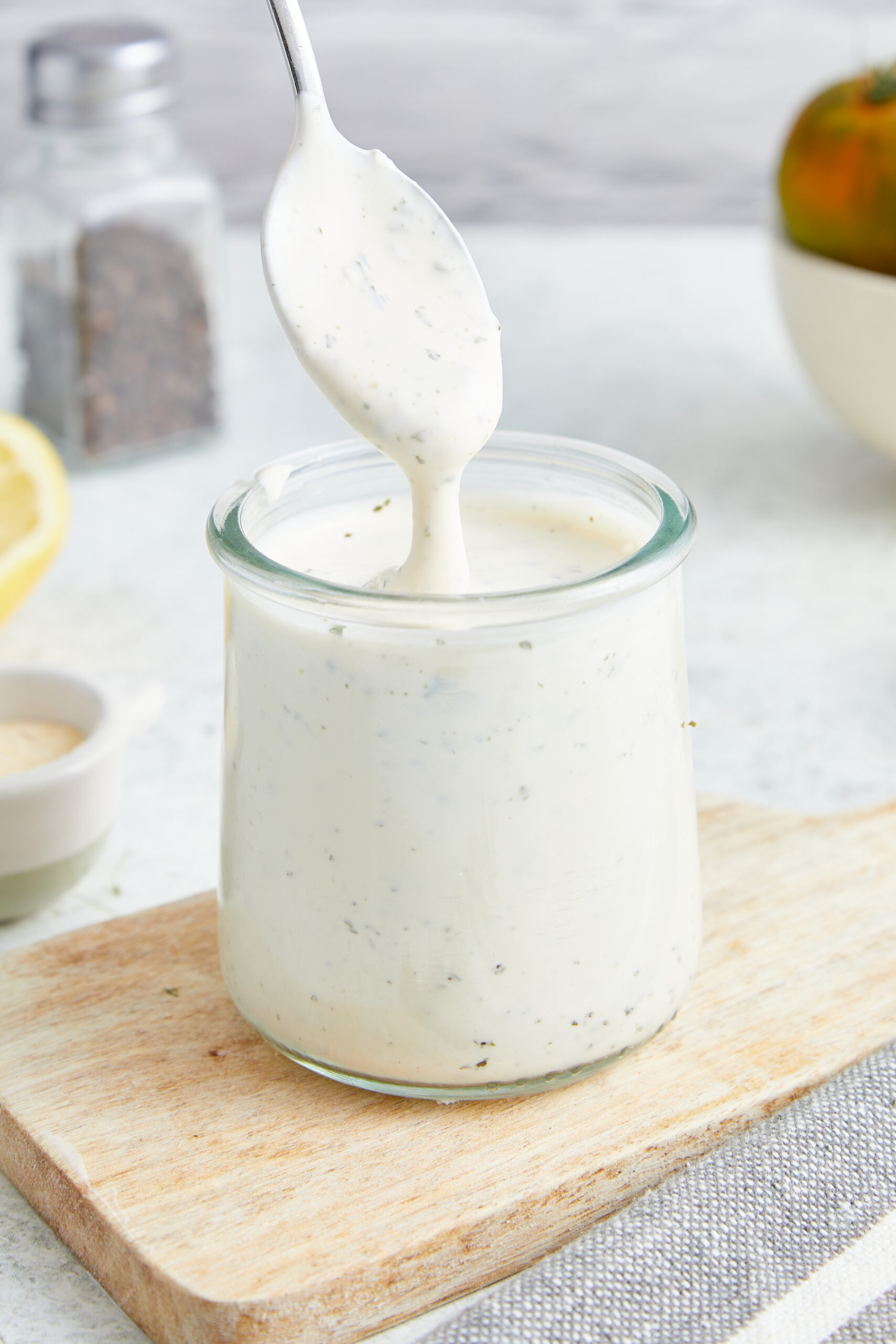 Homemade Ranch Dressing being scooped from a glass jar with a spoon, showing its creamy texture.