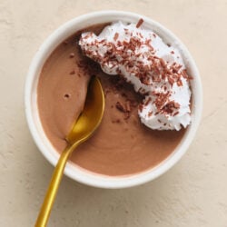 Pot De Cr&egrave;me in a white bowl, topped with whipped cream and chocolate shavings.