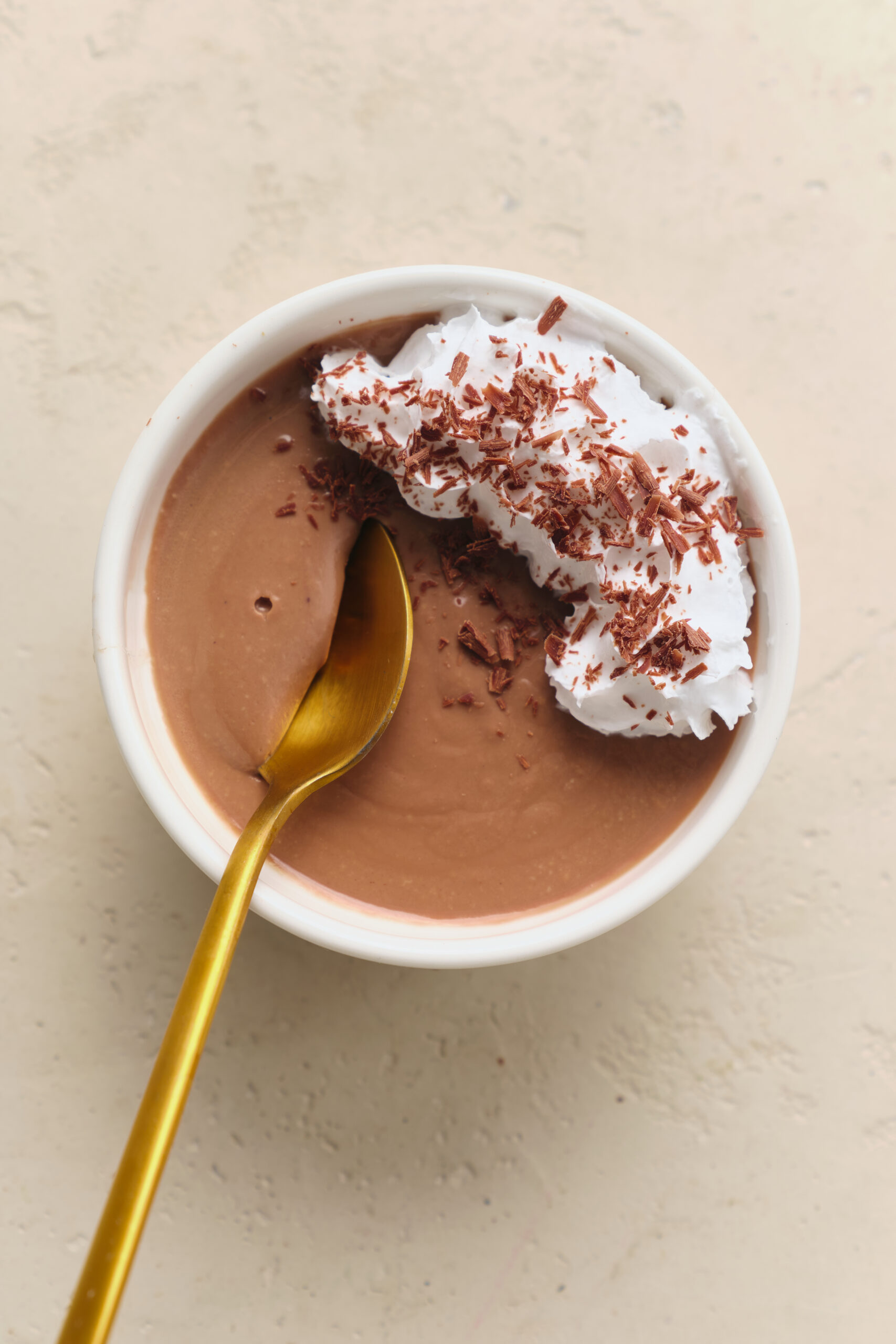 Pot De Cr&egrave;me in a white bowl, topped with whipped cream and chocolate shavings.