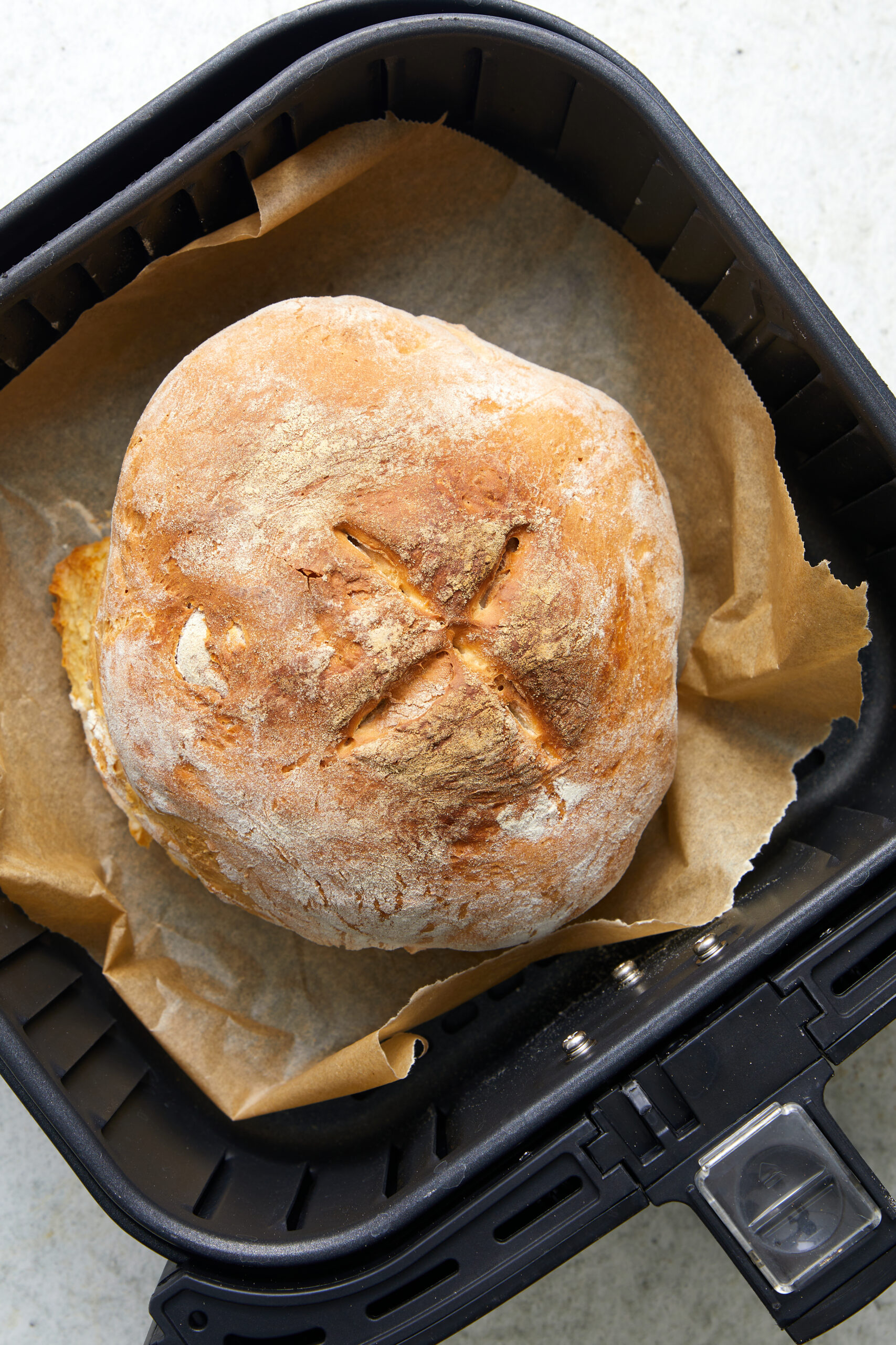 Golden brown Air-Fryer Bread with a scored top, resting in an air fryer basket.