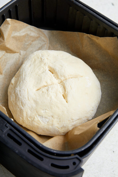 Scored Air-Fryer Bread dough in an air fryer basket.
