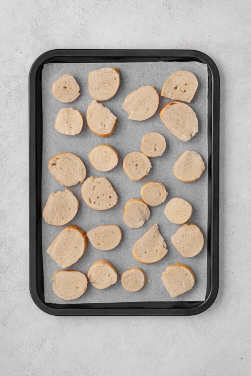 Thin bagel slices arranged on a baking sheet for Bagel Chips.