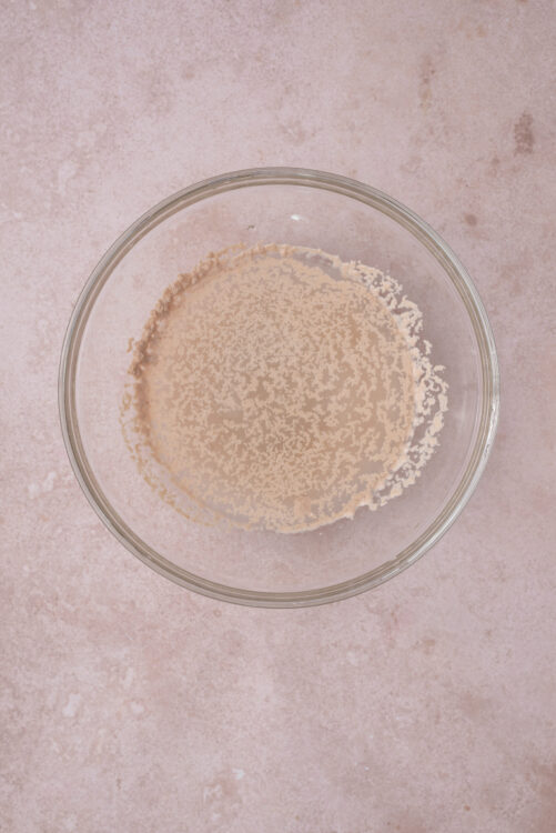 Activating yeast for blueberry bagels, frothing in a glass bowl.