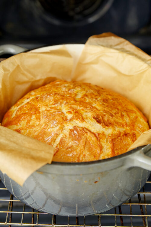 Golden brown cheese bread baking in a Dutch oven.