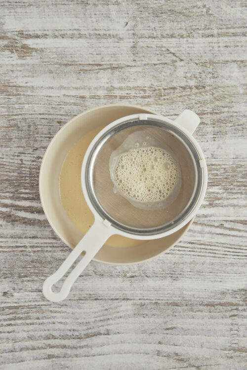 Straining the Cr&egrave;me Br&ucirc;l&eacute;e custard through a fine sieve into a clean bowl.