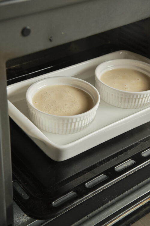 Cr&egrave;me br&ucirc;l&eacute;e custard baking in ramekins in the oven.