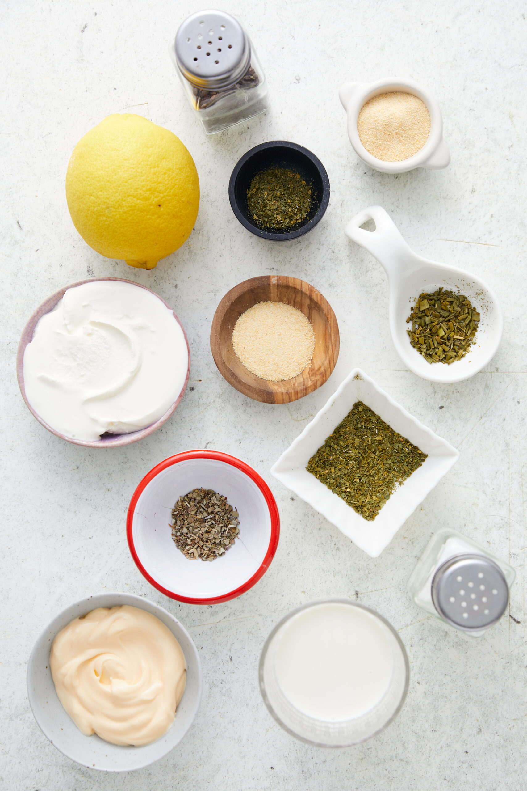 Ingredients for Homemade Ranch Dressing: lemon, sour cream, mayonnaise, buttermilk, dried herbs, onion powder, garlic powder, salt, and pepper.