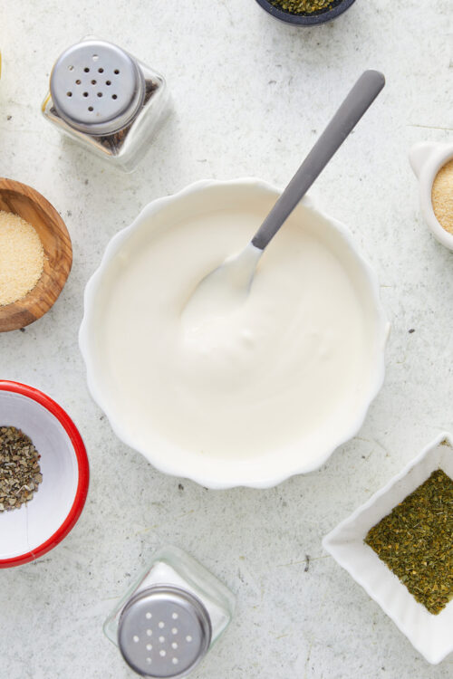 Homemade ranch dressing in a white bowl with a spoon.
