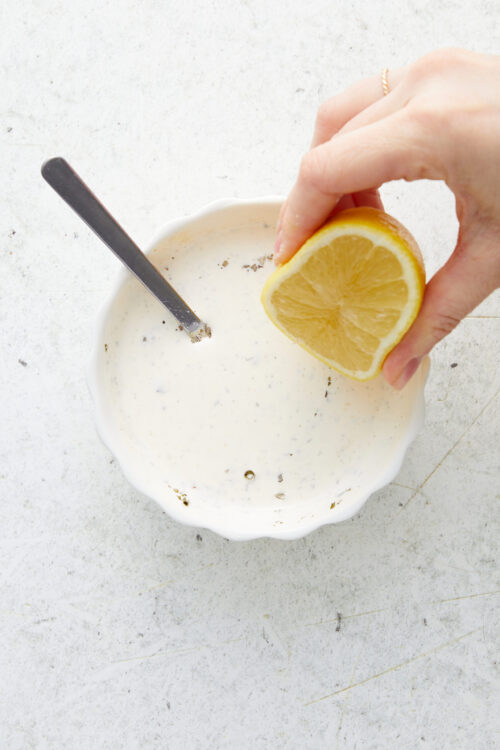 Squeezing fresh lemon juice into homemade ranch dressing.