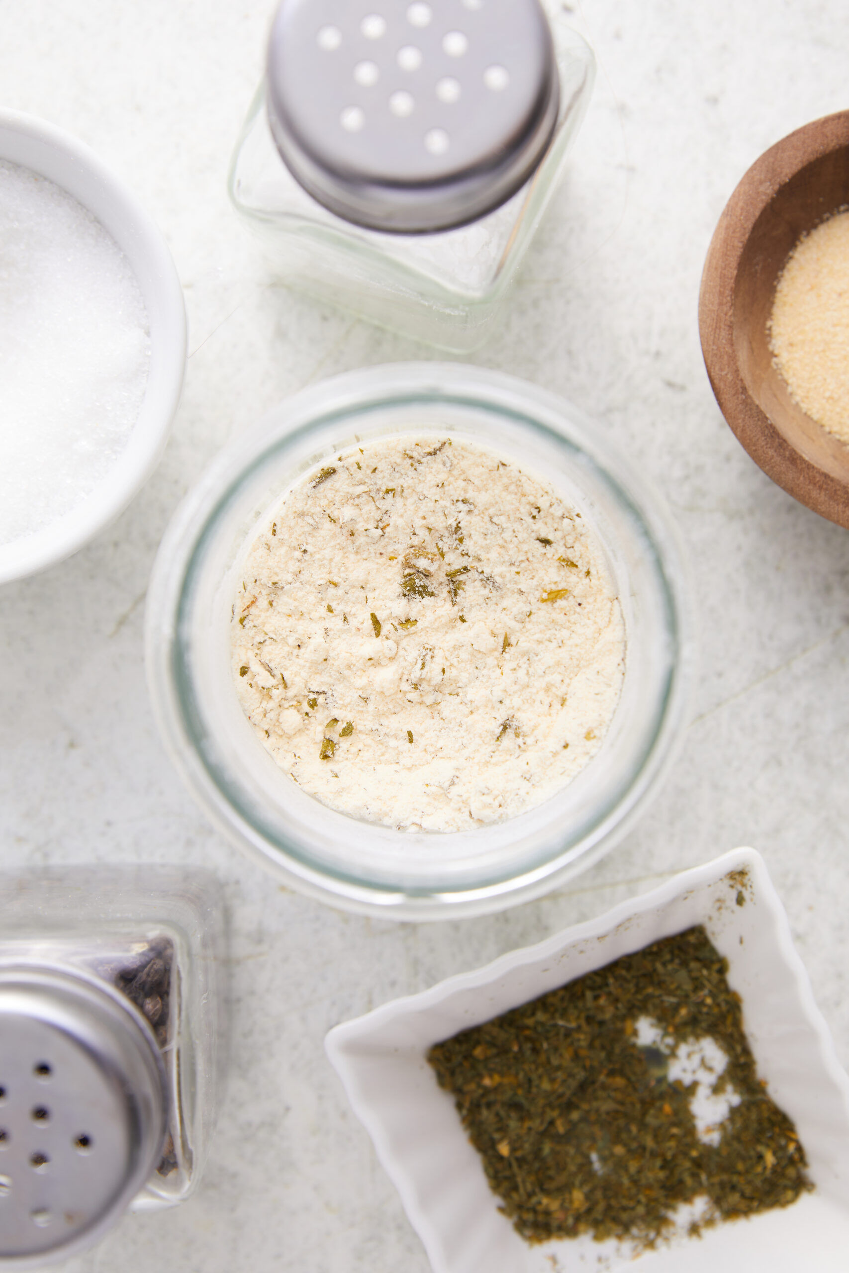 Homemade Ranch Seasoning in a glass jar, surrounded by salt, garlic powder, and dried herbs.