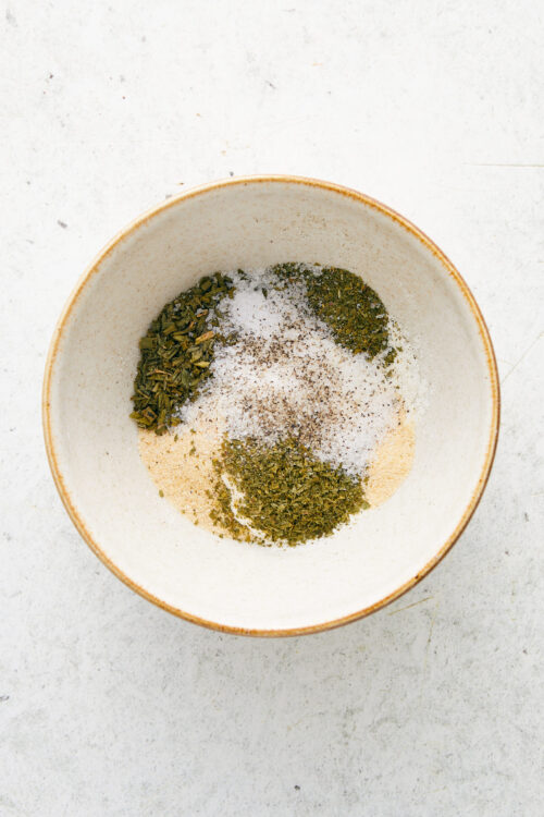 Placing spices and powders for homemade ranch seasoning into a bowl.