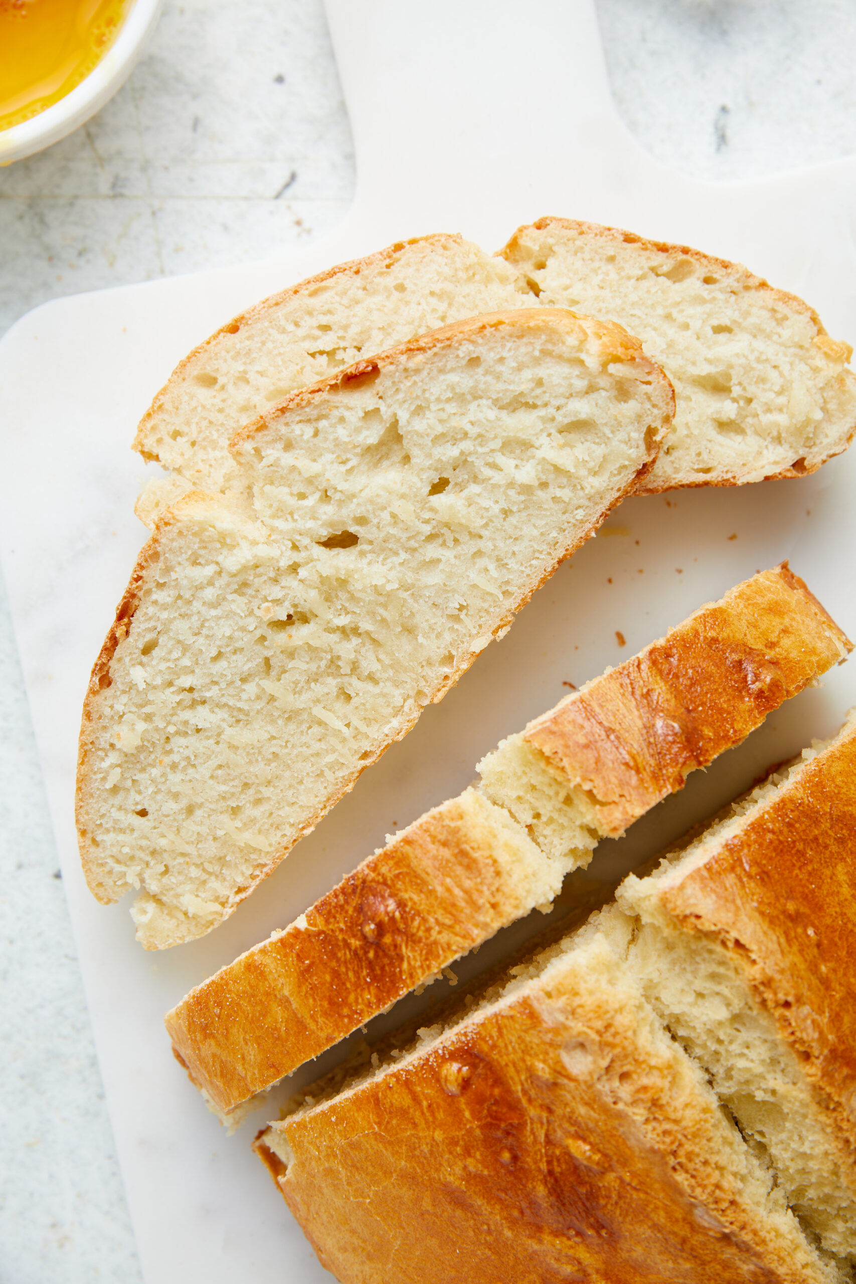 Slices of golden-brown Italian bread on a white cutting board, ready to serve.