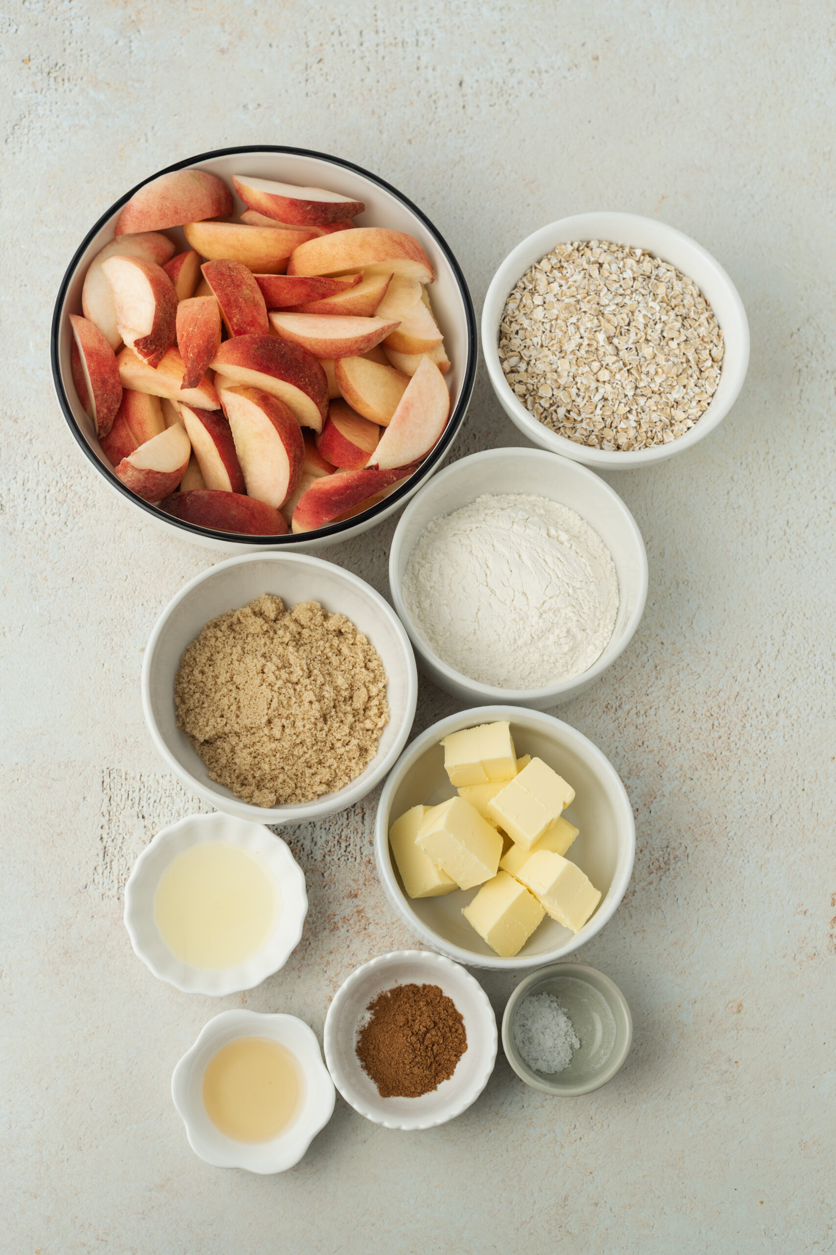 Ingredients for Peach Crisp Recipe: sliced peaches, rolled oats, all-purpose flour, brown sugar, butter, lemon juice, vanilla extract, cinnamon.