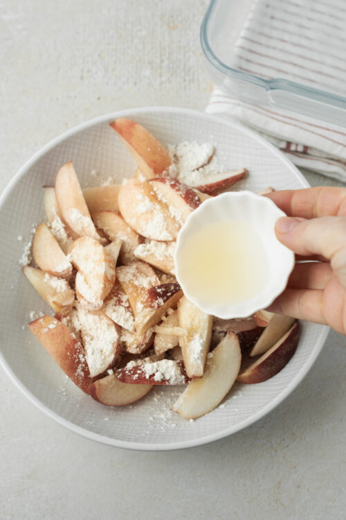 Peach crisp ingredients being tossed with cornstarch and lemon juice.