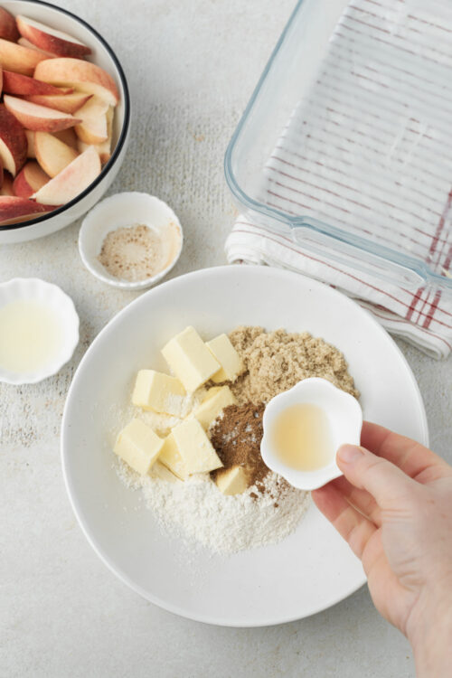 Adding vanilla to peach crisp topping ingredients.