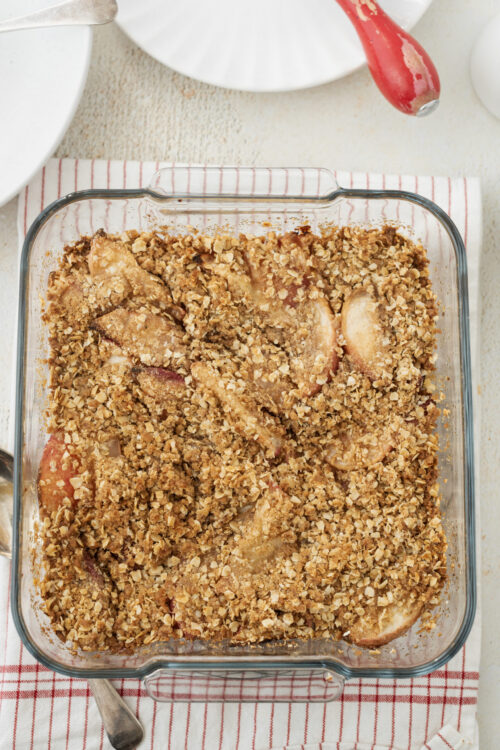 Baked peach crisp in a glass dish with an oat topping.