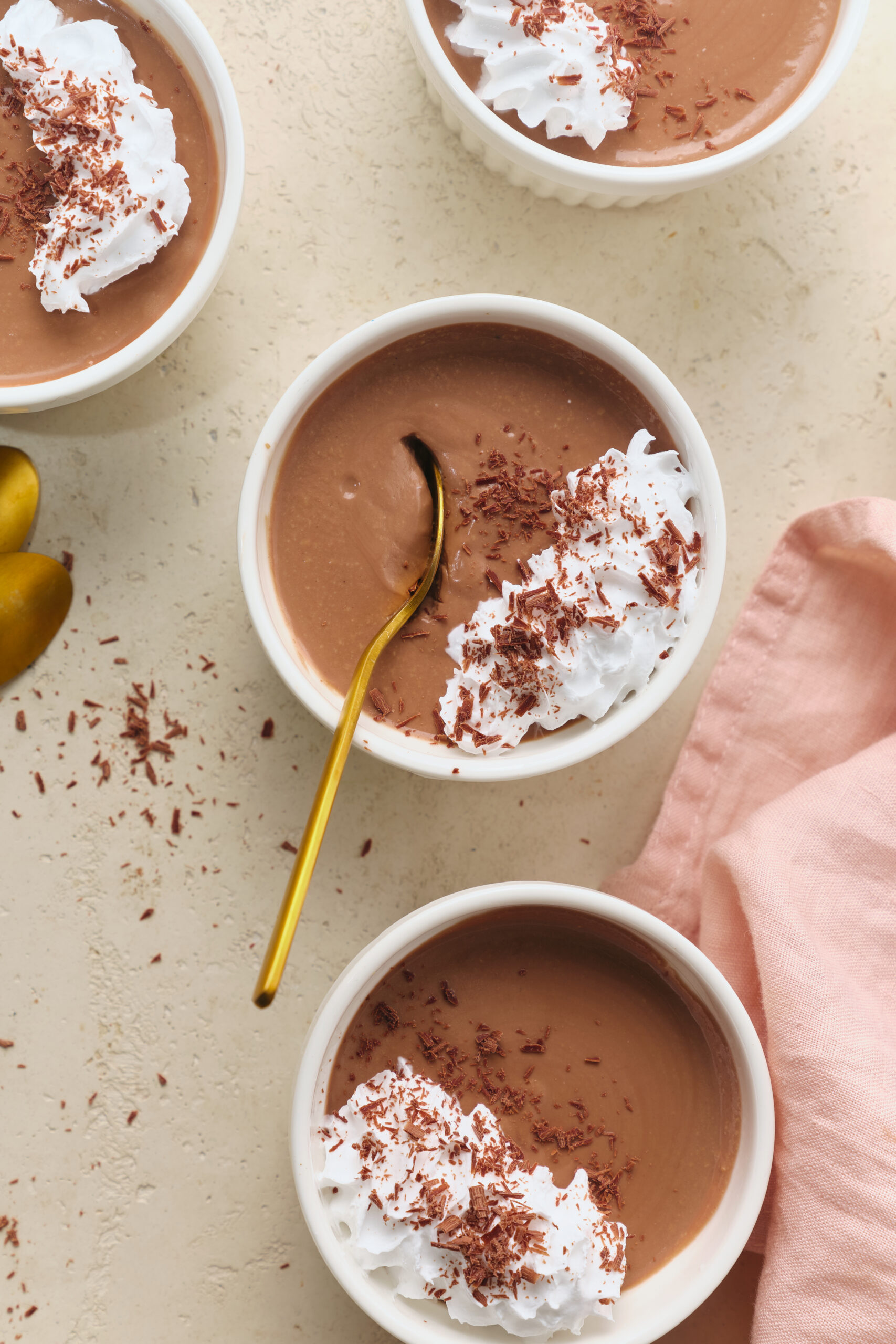 Three ramekins of chocolate Pot De Cr&egrave;me, topped with whipped cream and chocolate shavings.