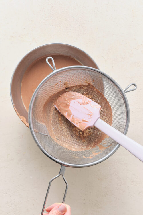 Straining the Pot De Cr&egrave;me custard through a fine mesh sieve to remove lumps.