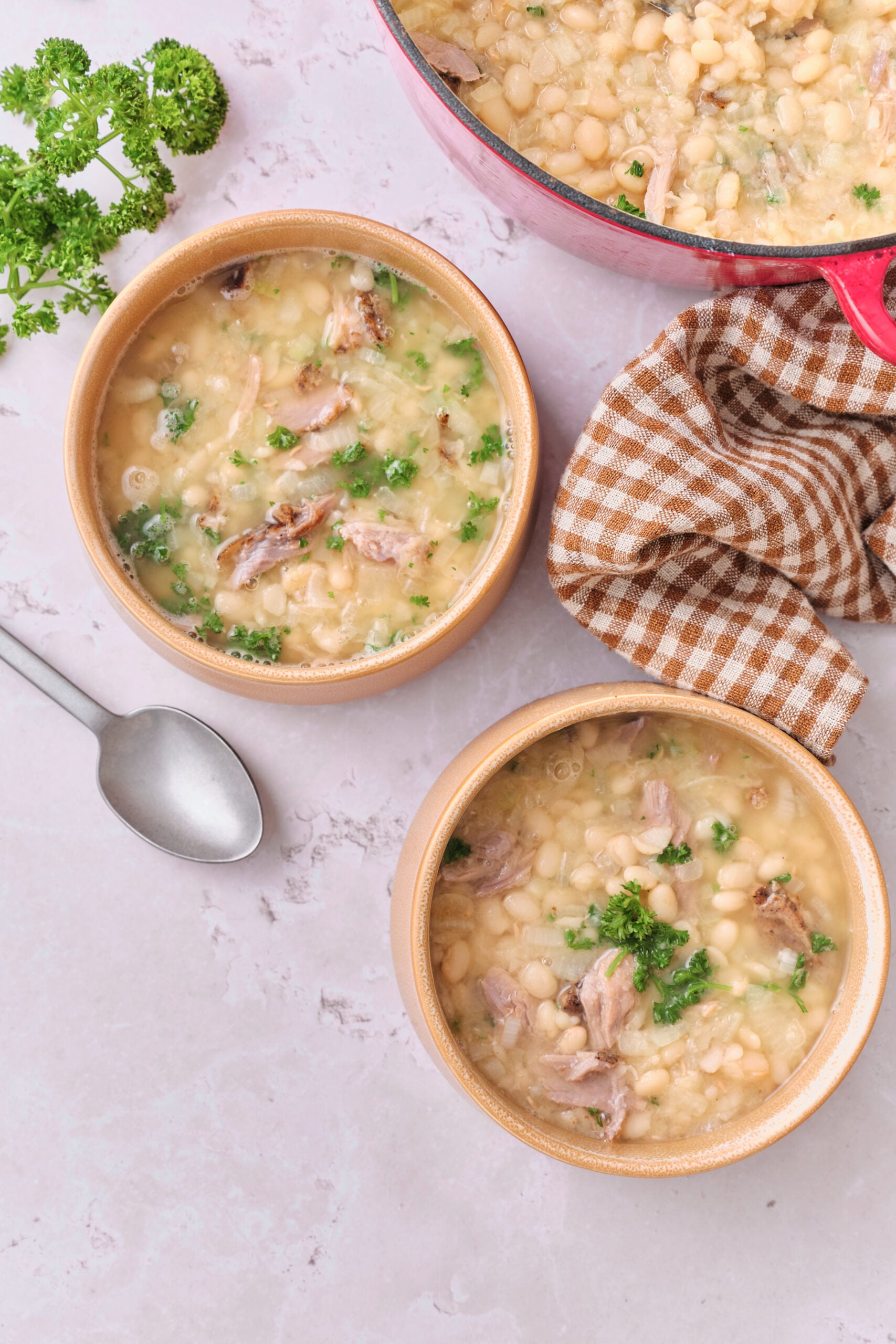 Two bowls of Senate Bean Soup with navy beans, shredded ham, and fresh parsley.