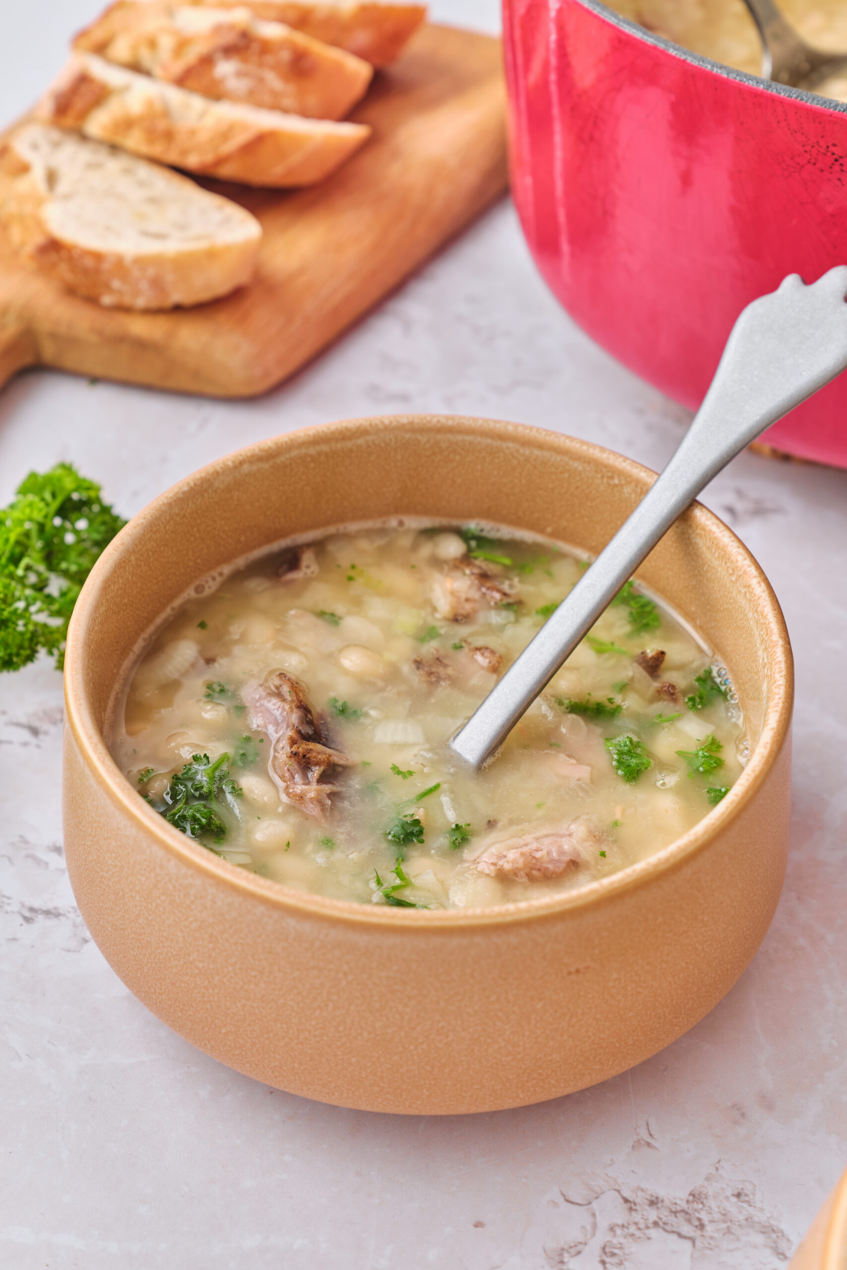 Senate bean soup in a beige bowl with shredded ham, navy beans, and fresh parsley.