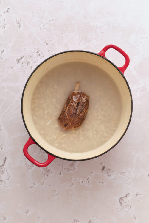 Adding navy beans, ham hock, and water to a pot for Senate Bean Soup.