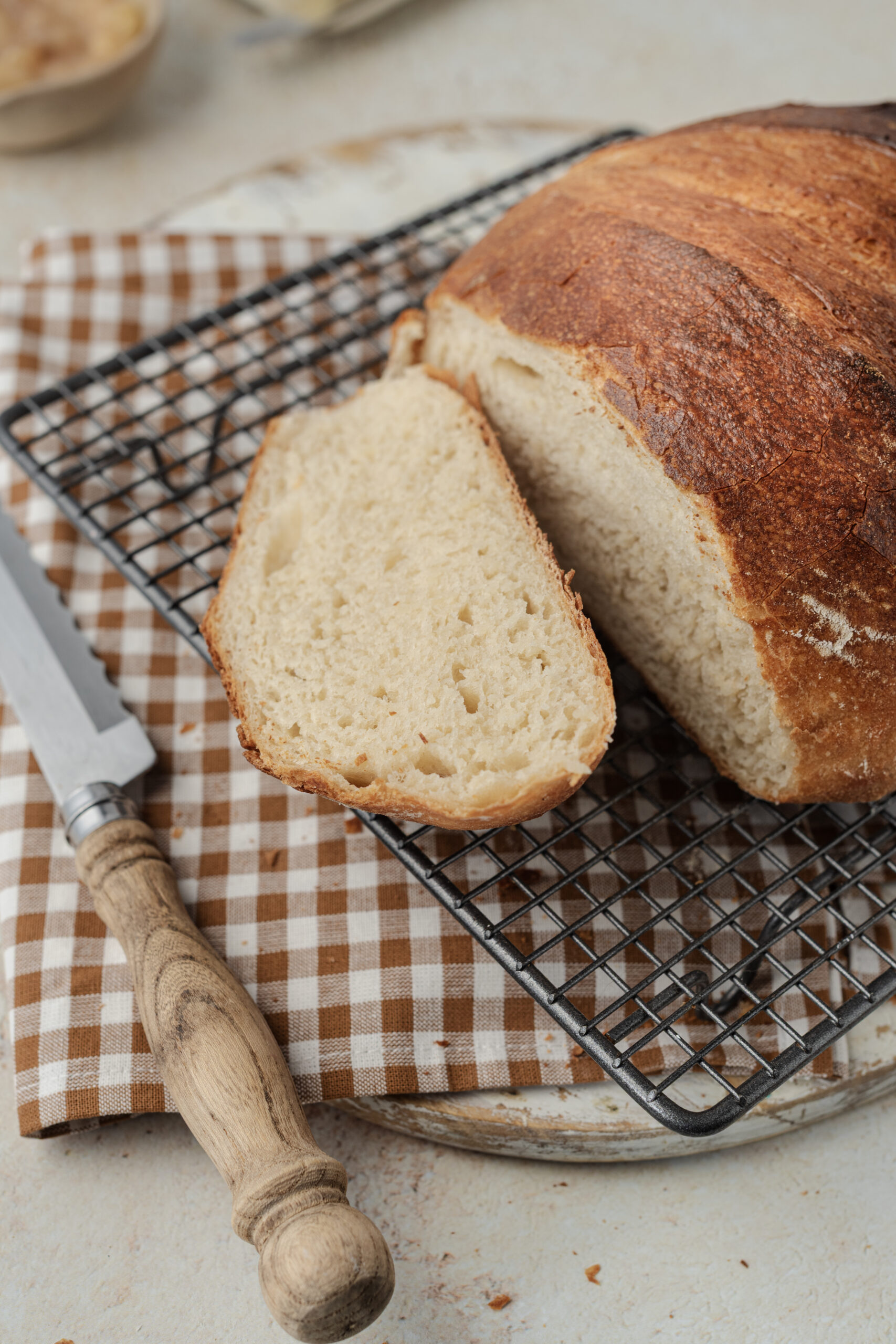 A freshly baked loaf of Artisan Bread, partially sliced, cooling on a wire rack.