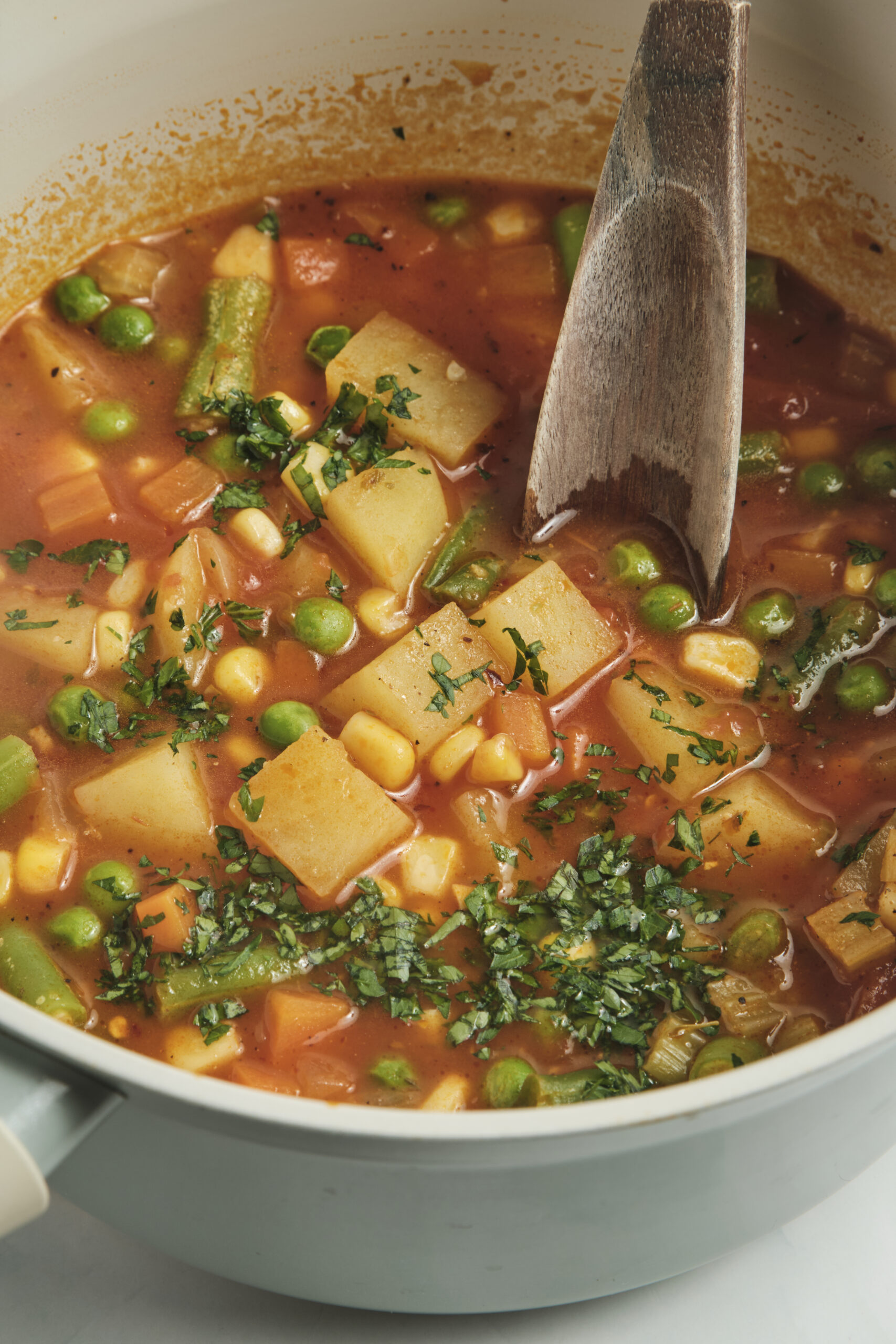 Vegetable soup with potatoes, peas, corn, green beans, and fresh parsley.