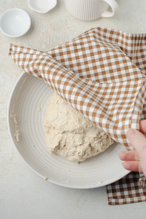 Artisan bread dough covered with a kitchen towel for rising.
