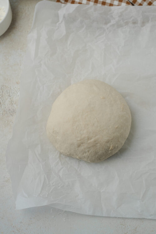 Artisan bread dough formed into a round loaf on parchment paper.