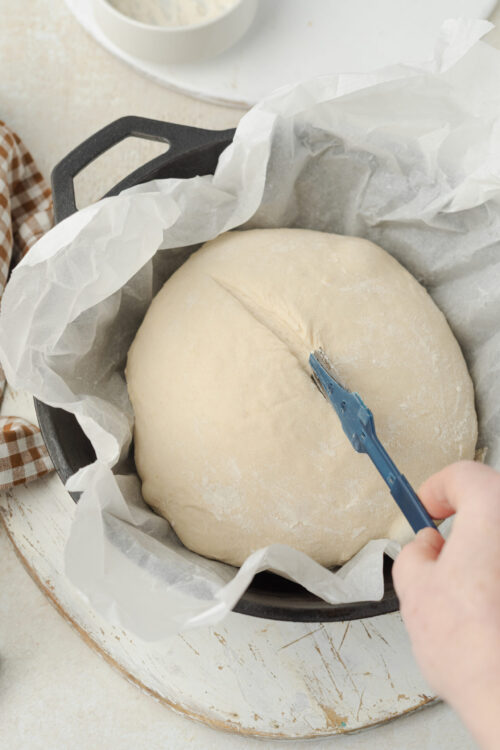 Scoring artisan bread dough in a Dutch oven.
