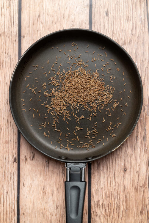 Toasting caraway seeds in a dry skillet for homemade harissa.