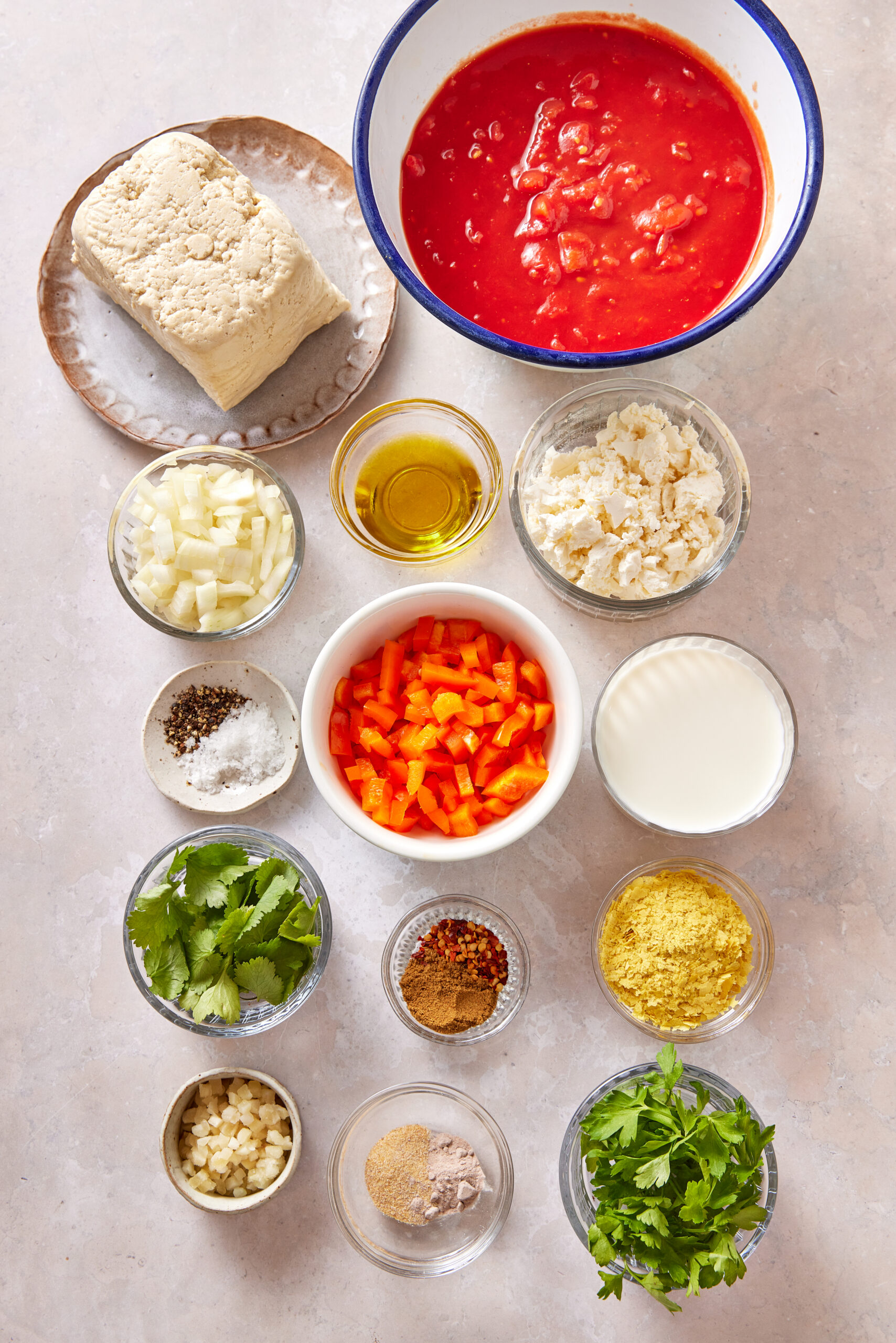Ingredients for Vegan Shakshuka Recipe: extra-firm tofu, diced tomatoes, chopped onion, red bell pepper, vegan feta cheese, fresh cilantro, and spices.