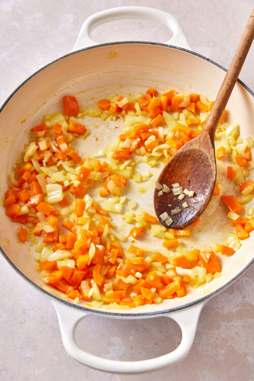 Cooking diced onion, bell pepper, and garlic in a skillet for vegan shakshuka.