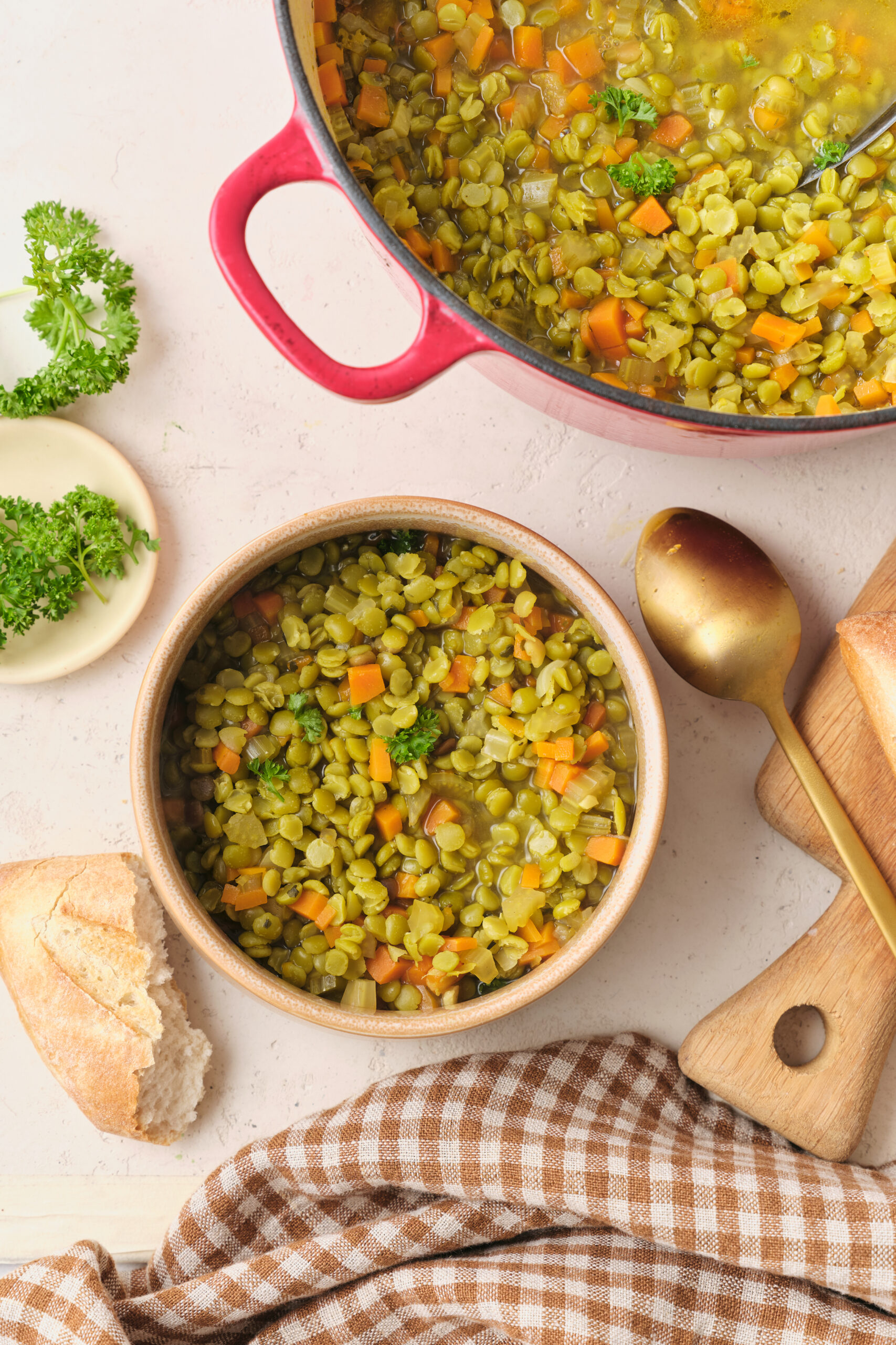 Vegan Split Pea Soup in a bowl, garnished with fresh parsley and served with crusty bread.