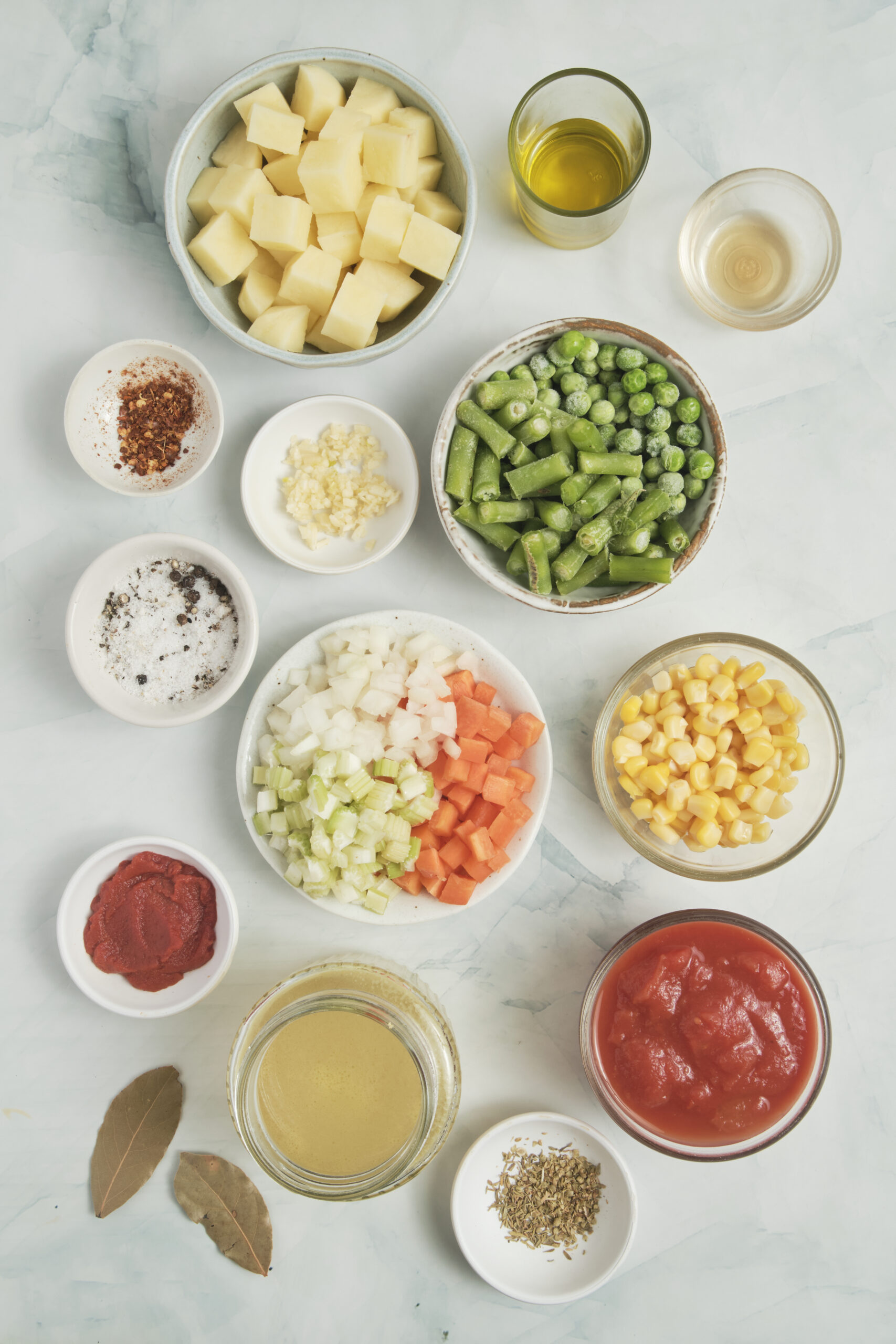 Ingredients for Vegetable Soup Recipe: diced potatoes, onion, carrots, celery, green beans, peas, corn, and diced tomatoes.