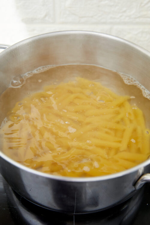 Penne pasta boiling in a pot for vodka sauce.