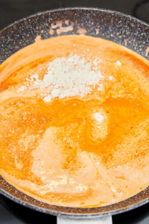 Vodka sauce in a skillet with grated Parmesan cheese.